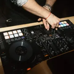 DJ miksuje muzykę na konsoli, tworząc atmosferę imprezy. Zastanawiasz się, ile kosztuje dj na imprezę?