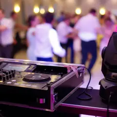 DJ przy konsoli, ludzie tańczą na weselu. Zastanawiasz się, ile bierze DJ za wesele?