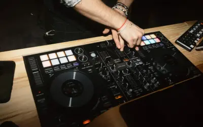 DJ miksuje muzykę na konsoli, tworząc atmosferę imprezy. Zastanawiasz się, ile kosztuje dj na imprezę?