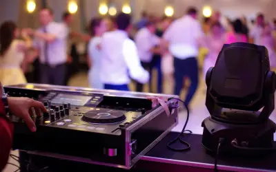 DJ przy konsoli, ludzie tańczą na weselu. Zastanawiasz się, ile bierze DJ za wesele?