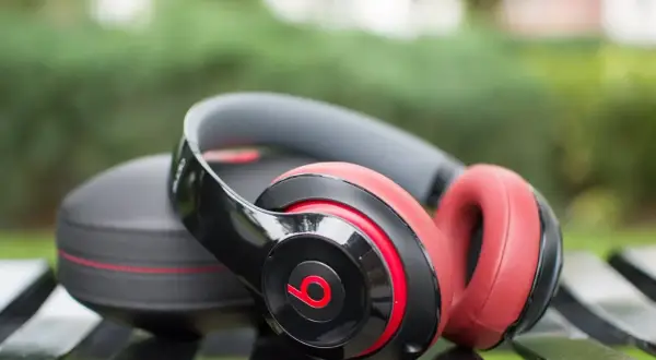 Czarne i czerwone słuchawki bezprzewodowe Beats Studio leżą obok etui na ławce. Idealne, jeśli zastanawiasz się, jakie słuchawki bezprzewodowe wybrać.